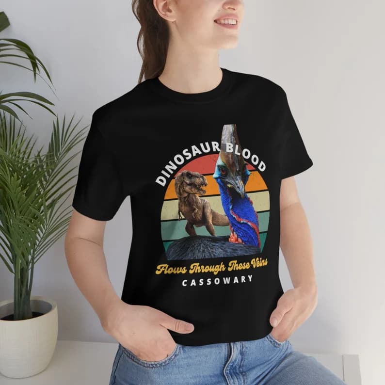 Woman wearing Cassowary t-shirt with dinosaur image and wording "Dinosaur blood flows through these veins - cassowary"